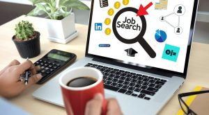 osoba pijąca kawę przed komputerem porównująca strony z ofertami pracy|