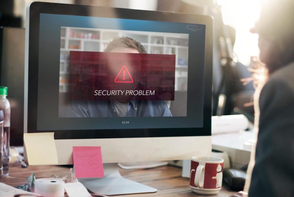 Zdjęcie jest ilustracją do artykułu: Rekrutacja zdalna a ochrona danych osobowych kandydata – na co zwrócić uwagę? Przedstawia rozmowę video dwóch osób. Na ekranie komputera widnieje znak ostrzeżenia i napis " Security Problem"|Rekrutacja zdalna a ochrona danych osobowych kandydata do pracy – na co zwrócić uwagę?|Rekrutacja zdalna a ochrona danych osobowych kandydata do pracy – na co zwrócić uwagę?|