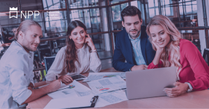 Zdjęcie jest ilustracją do artykułu: Najbardziej Pożądani Pracodawcy w Polsce – znamy laureatów rankingu firmy Antal. Przedstawia grupę pracowników siedzących przy stole konferencyjnym i patrzących na ekran laptopa. Na stole leżą wydruki||||