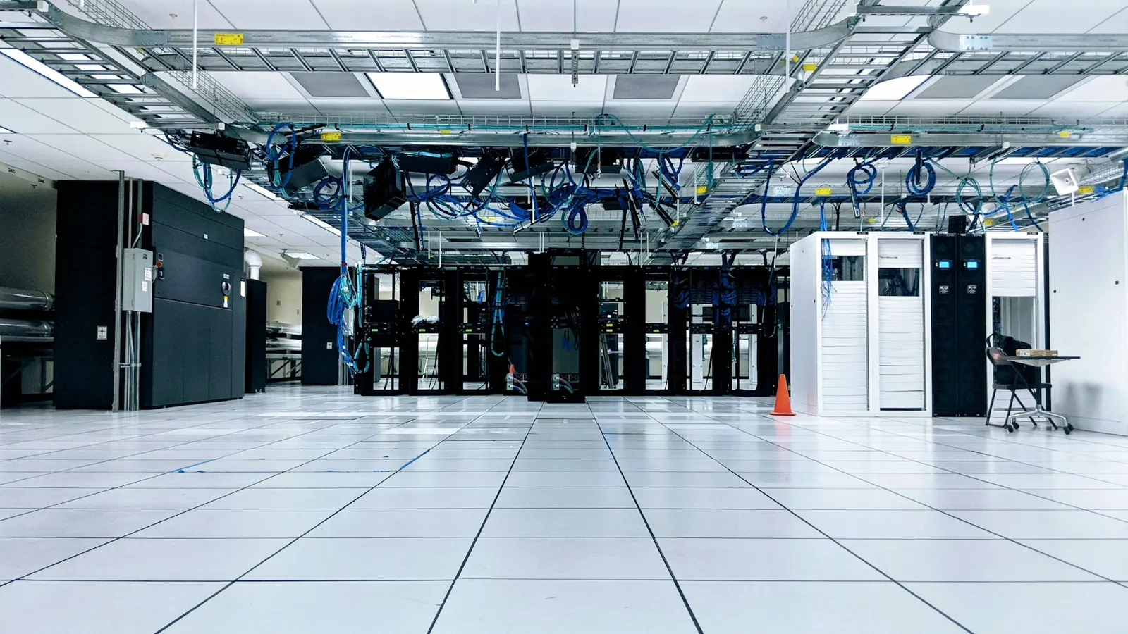Data centre hall with rows of server cabinets and overhead cabling