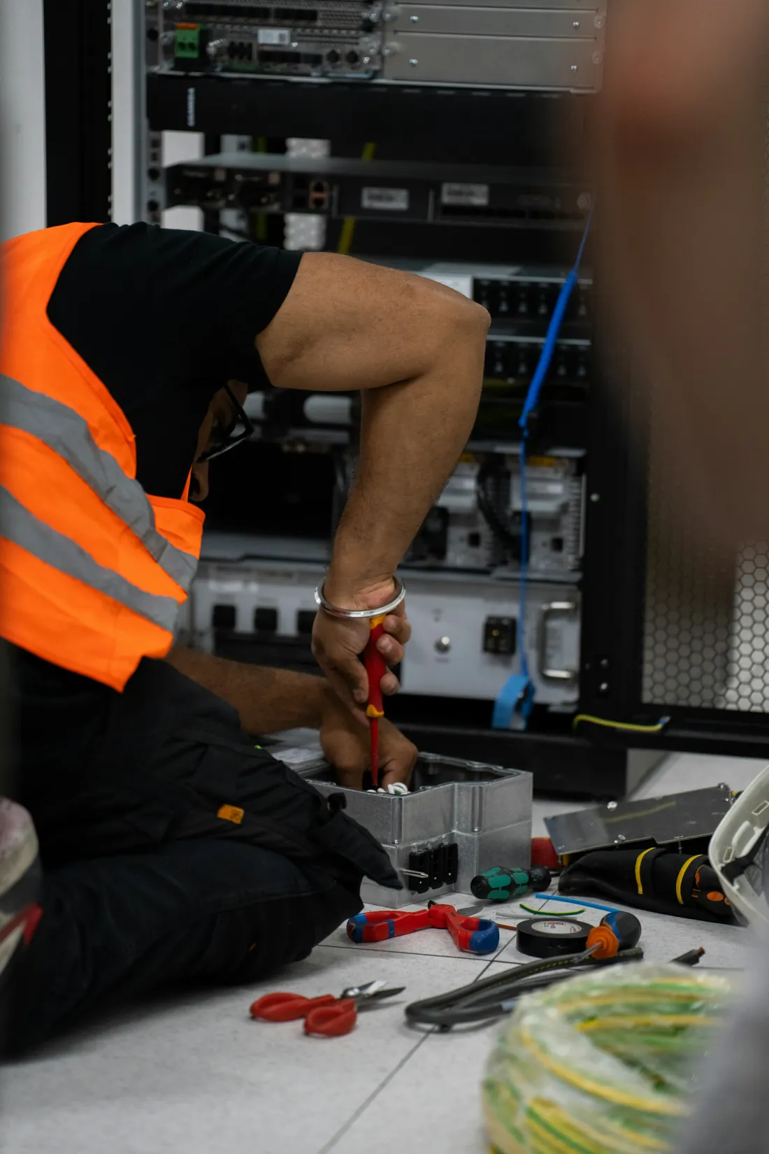 Technician working on electrical connections at a data centre rack
