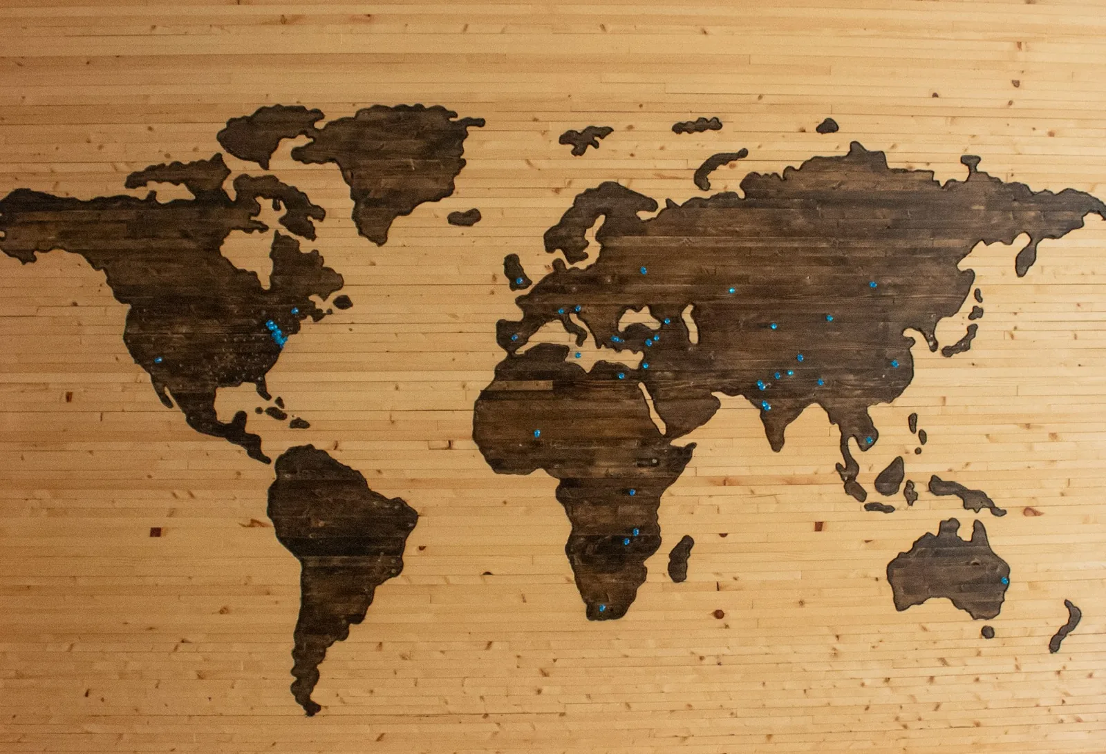 Wooden world map with pins marking international locations